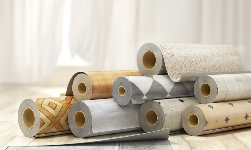 Deux hommes installent du papier peint à motifs ornementaux beige dans un intérieur résidentiel avec moulures blanches