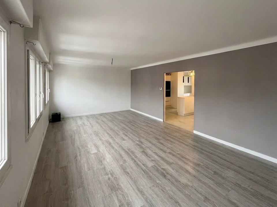 Un homme mesure et marque des lames de parquet en bois naturel dans un intérieur en cours d'aménagement